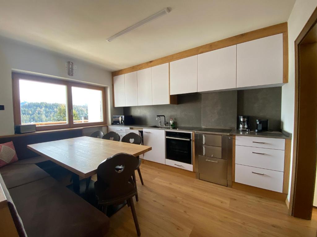 安特尔莫伊亚Ampio appartamento di 200mq nel cuore di Antermoia的厨房配有白色橱柜和木桌