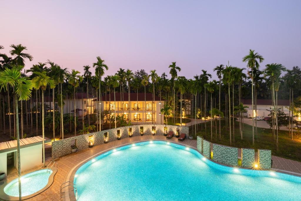 希莫加Malnad Shire Eco Resort的一座棕榈树游泳池和一座建筑
