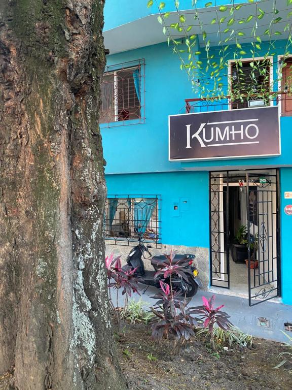 麦德林Hostel Kumho alojamiento的蓝楼,树旁有标志