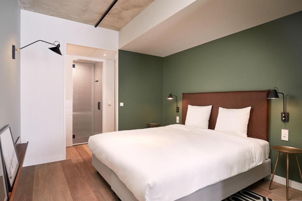 巴德胡弗多普Corendon Apartments Amsterdam Schiphol Airport的卧室设有一张白色大床和绿色的墙壁