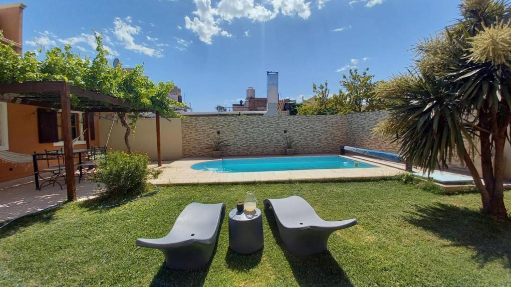 岑特纳里奥Casa Girasoles的后院设有游泳池、2把椅子和1张桌子