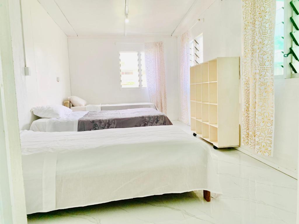 FolahaTonga Cottage - Triple Room with Shared Facilities的一间白色卧室,配有两张床和橱柜