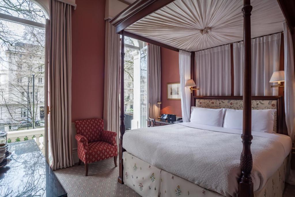 伦敦皇家公园酒店的一间卧室配有一张天蓬床和一把椅子