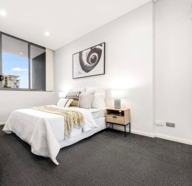 悉尼Cozy stylish home in Rhodes的白色卧室配有一张大床和一张桌子