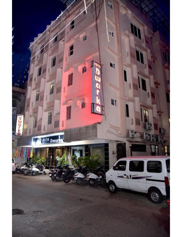 那格浦尔Hotel Dwarka, Nagpur的一辆停放在一座带摩托车的建筑前的白色货车