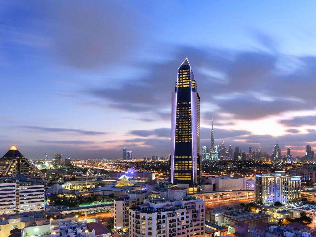 迪拜Sofitel Dubai The Obelisk的夜晚在城市里高耸的摩天大楼