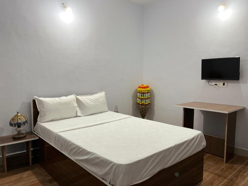 KharakvaslaLotus Guest House的一间卧室配有一张床,墙上配有电视