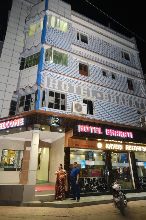德奥加尔Hotel Bharati的站在旅馆前面的男人和女人