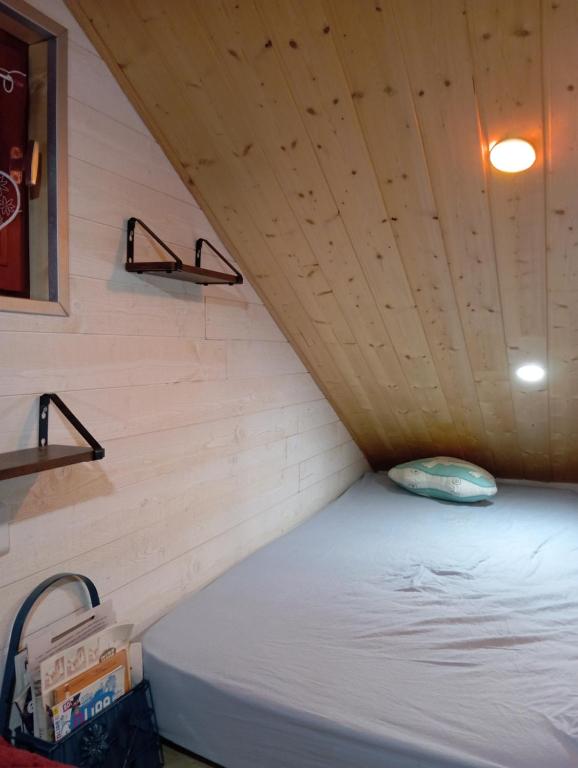 Ménétrux-en-JouxLa p'tite maison bois du hérisson的小型客房的一张床位,设有木制天花板