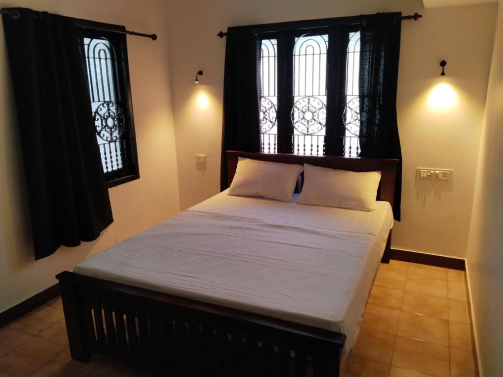 科钦The Chill House的一张大床,位于带两个窗户的房间