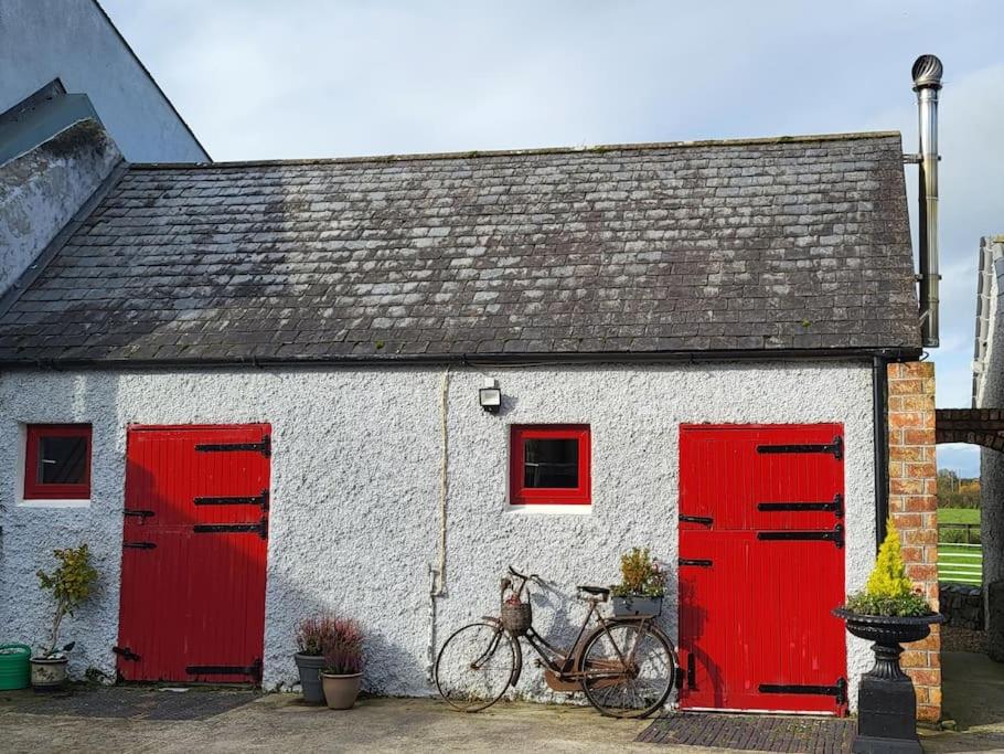 BennettsbridgeThe Stable, Bennettsbridge, Kilkenny的一辆停在白色建筑前的自行车,有红色的门