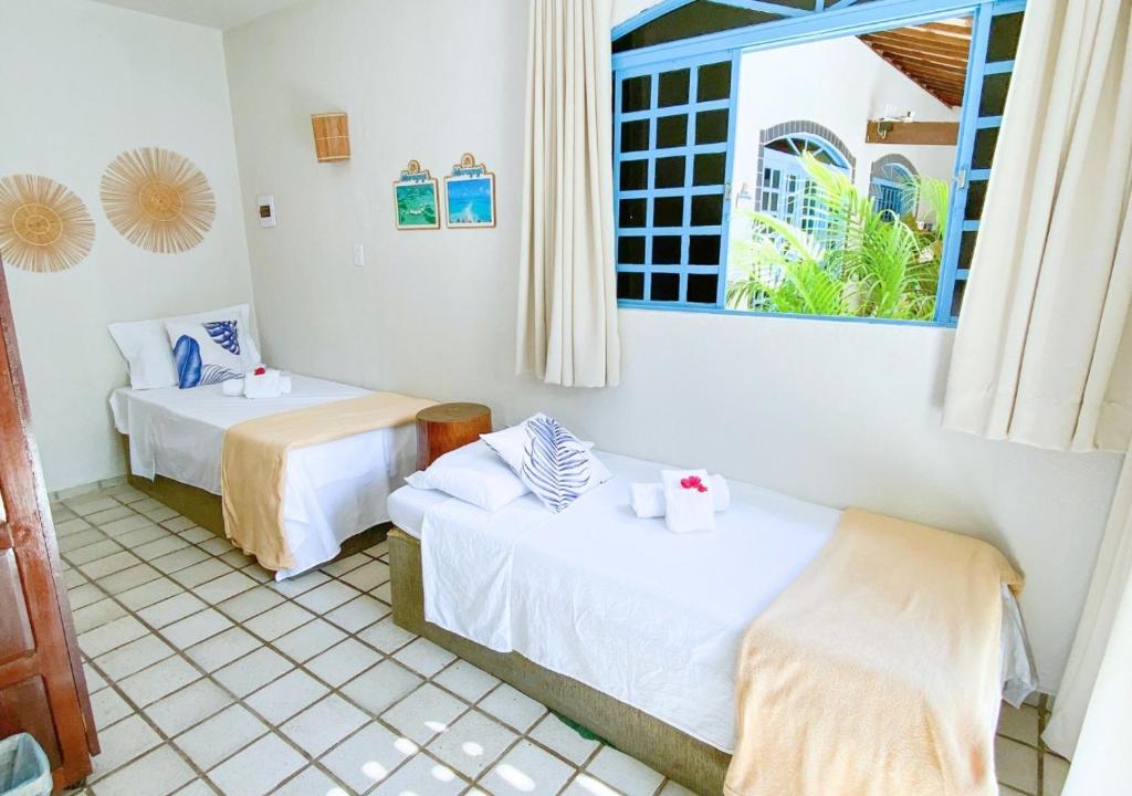 圣米格尔-杜斯米拉格里斯Pousada Praias do Norte的客房设有两张床和窗户。