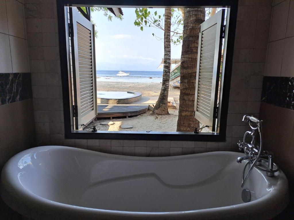 珀尼达岛Beach House Penida的带浴缸的浴室,享有海滩美景