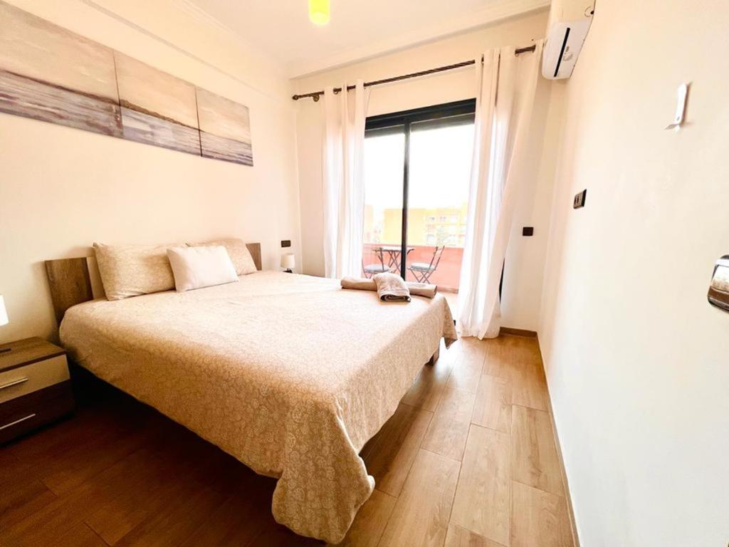 马拉喀什Beautiful apartment in gueliz with swimming pool的一间卧室设有一张大床和一个大窗户