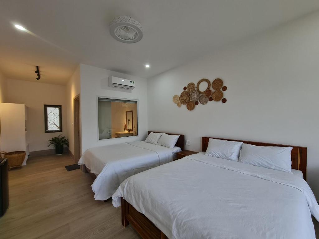 潘郎Myhoa Lagoon - Kiting Town的配有白色墙壁和木地板的客房内的两张床