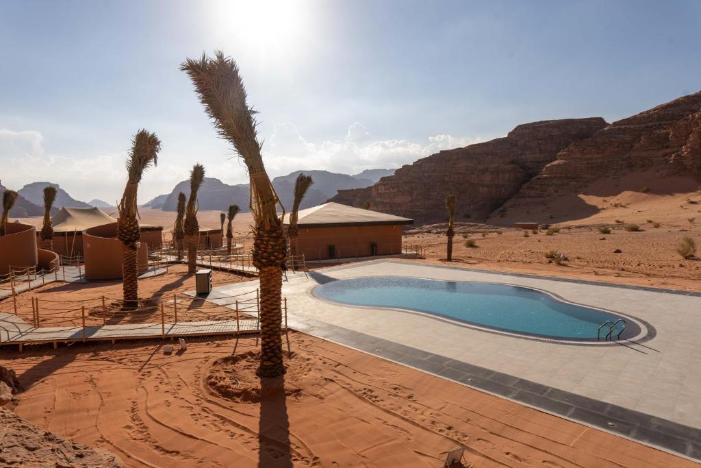 瓦迪拉姆Valley Resort的沙漠中的棕榈树游泳池和一座建筑