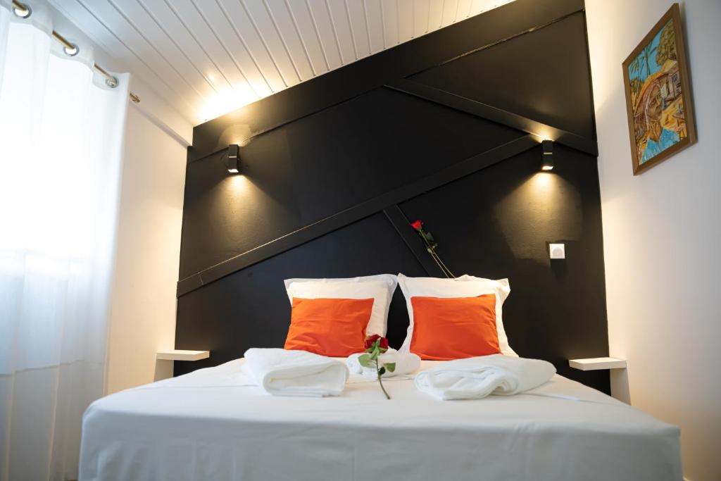 卡宴L'élégance citadine的一张带两个橙色枕头和黑色床头板的床