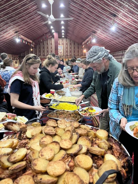 瓦迪拉姆哈立德营地酒店的一群人站在餐桌旁,吃着各种食物