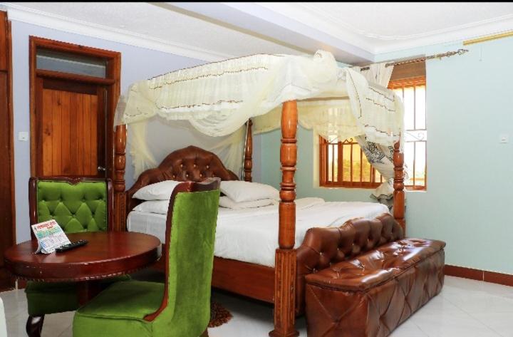 MubendePrimeRose Hotel Mubende的一间卧室配有一张天蓬床、一张桌子和一把椅子