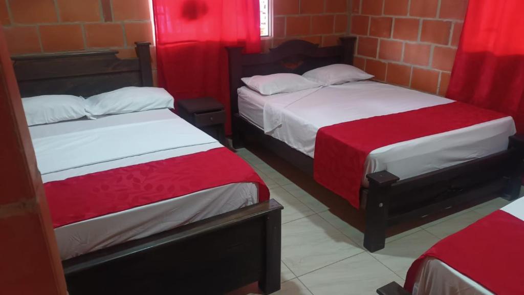 内瓦Hotel campestre la isla的配有红色窗帘的客房内的两张床