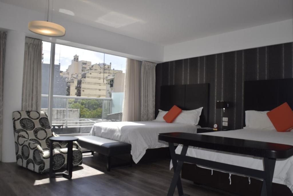布宜诺斯艾利斯Hotel BA Abasto的酒店客房设有两张床、一张书桌和一个窗户。