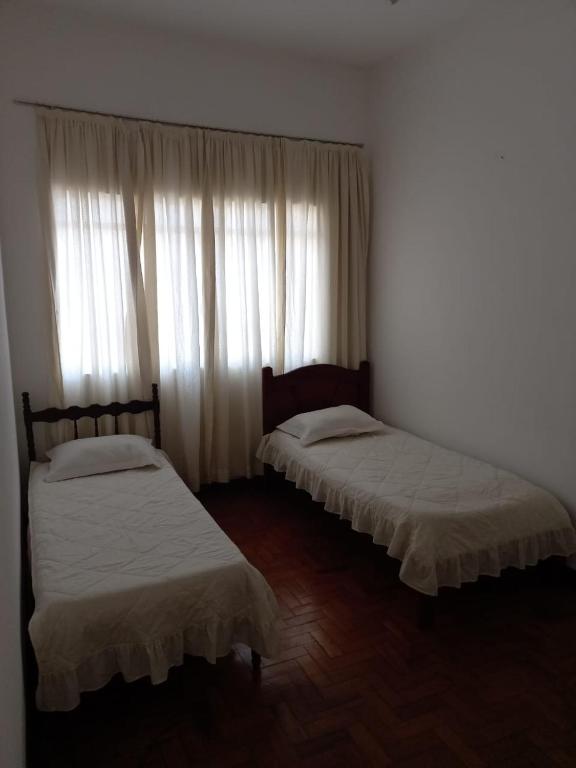 沃尔塔雷东达Apartamento MOBILIADO 2 QUARTOS的配有窗帘的窗户的客房内的两张床