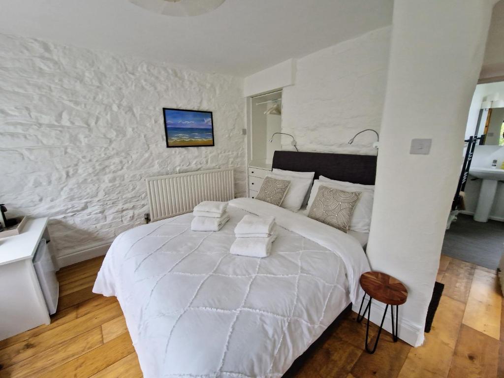赫尔斯顿Primrose Cottage的白色的卧室设有一张大床和一面墙