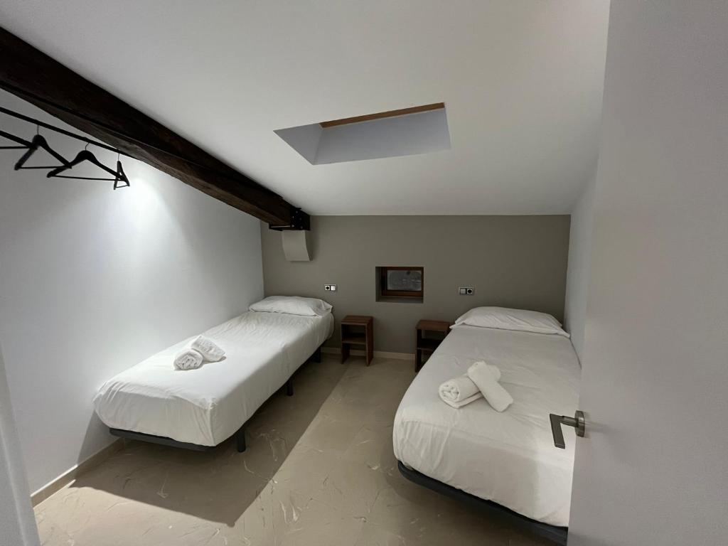 索尔索纳Antiga Biblioteca的小客房内的两张床,配有白色床单