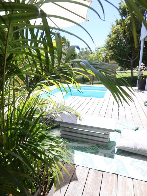 克尼斯纳Lush Spacious Family Home between Beach & Town的一个带木甲板和棕榈树的游泳池