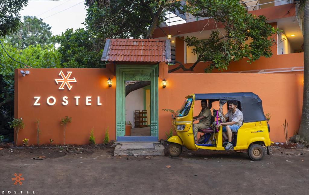 蓬蒂切里Zostel Pondicherry, Auroville Road的三人坐在大楼外的一辆小汽车里