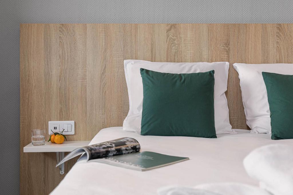 勒布伊阿布里酒店的一张带绿色枕头的床和一本书