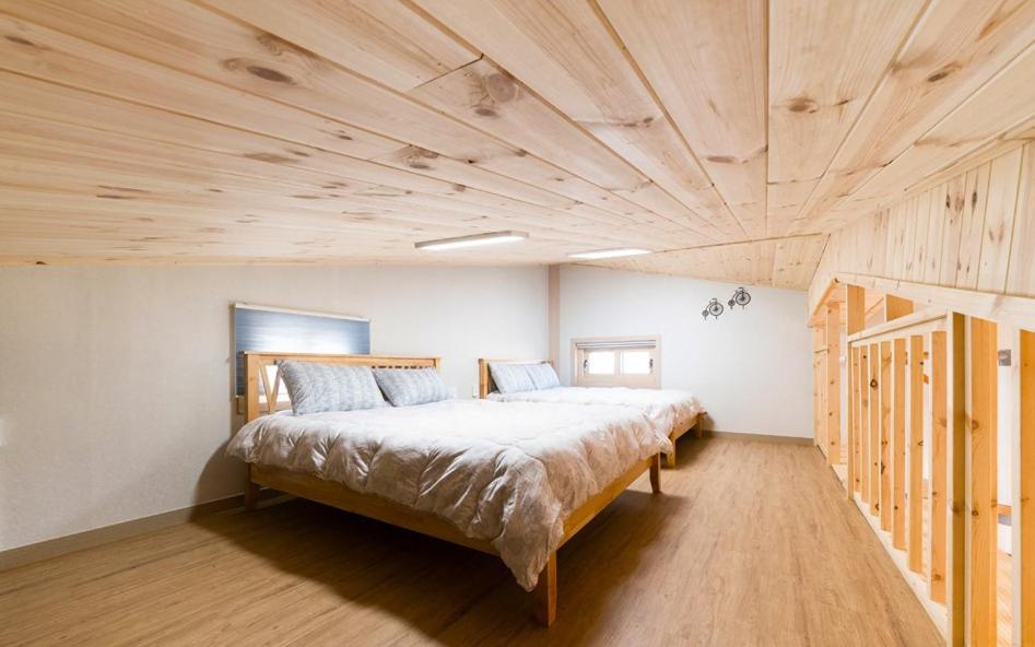 济州市Geumdanyoung Pension的一间卧室设有一张带木制天花板的大床