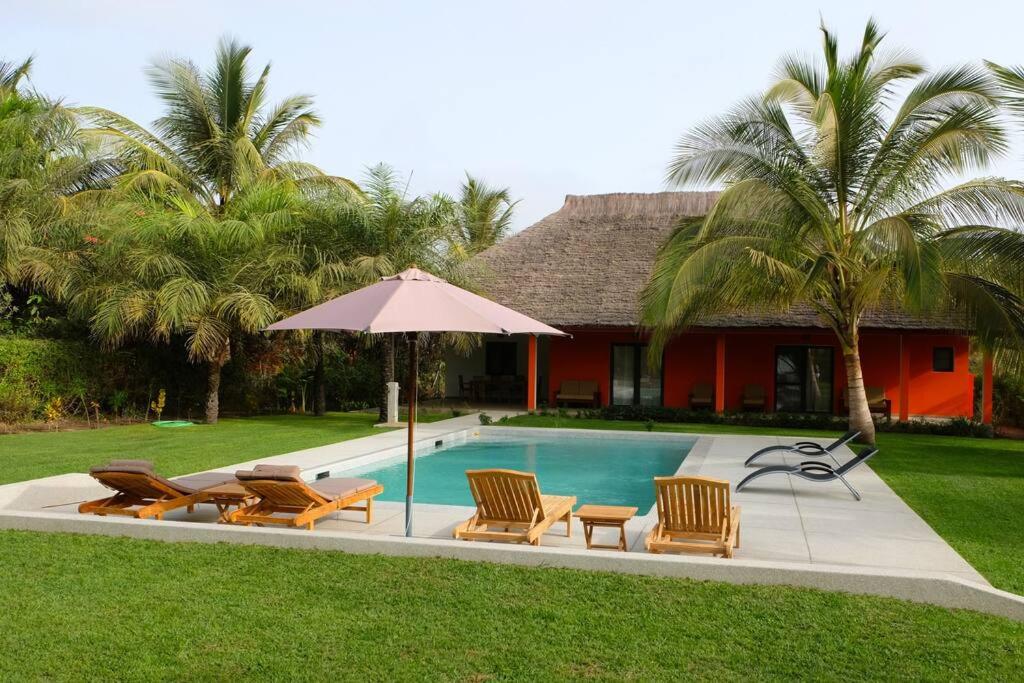 斯基灵角Villa avec piscine près de l'océan.的房屋旁的游泳池配有椅子和遮阳伞