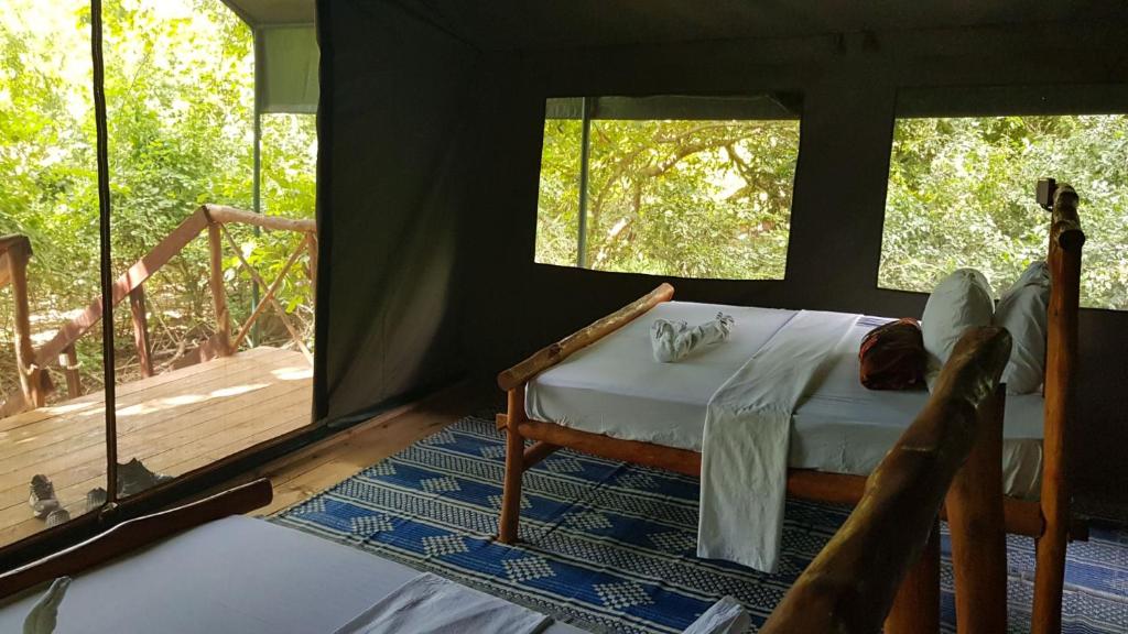 KwangwaziCamp Seluu - Safari Pkg的一间卧室配有一张床,甲板配有窗户
