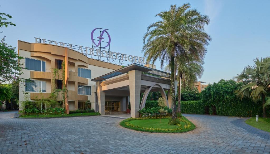 尼杜巴塞莱Flora Airport Hotel and Convention Centre Kochi的前面有棕榈树的建筑