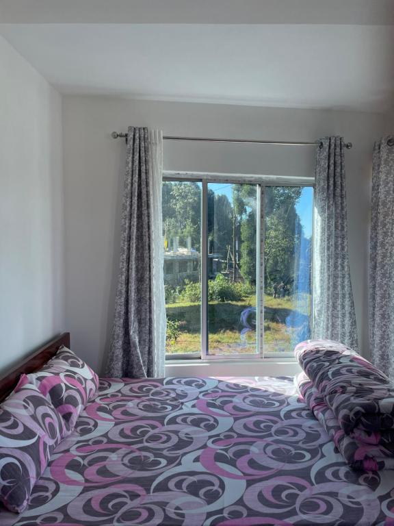 大吉岭Jasmine Homestay Darjeeling的一间卧室设有一张床和一个大窗户