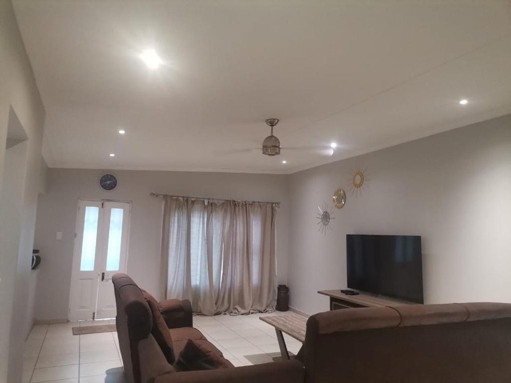 东伦敦Teke's cheerful 3 bed room villa with swimming pool的客厅配有2张沙发和1台平面电视