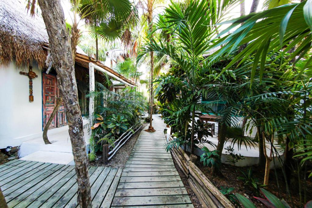 图卢姆Hotel Cormoran Tulum & Cenote的通往棕榈树房屋的木制走道