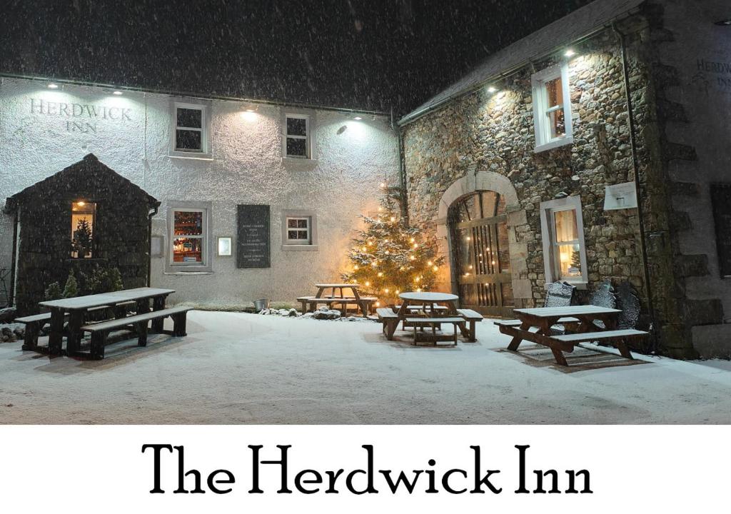 PenruddockThe Herdwick Inn的一群在建筑物前雪地里野餐桌