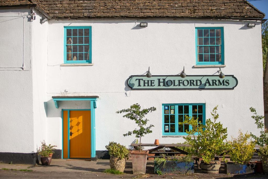 泰特伯里The Holford Arms的带有读取荷尔顿手臂的标志的白色建筑