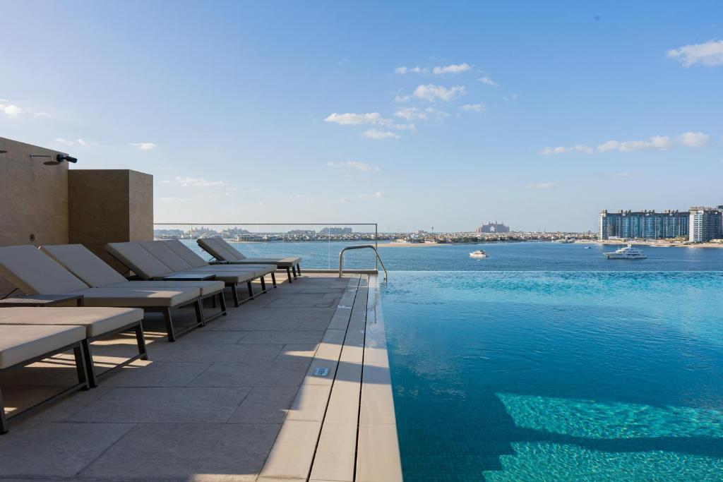 迪拜YOUR STAY APARTMENTS的水边带躺椅的游泳池