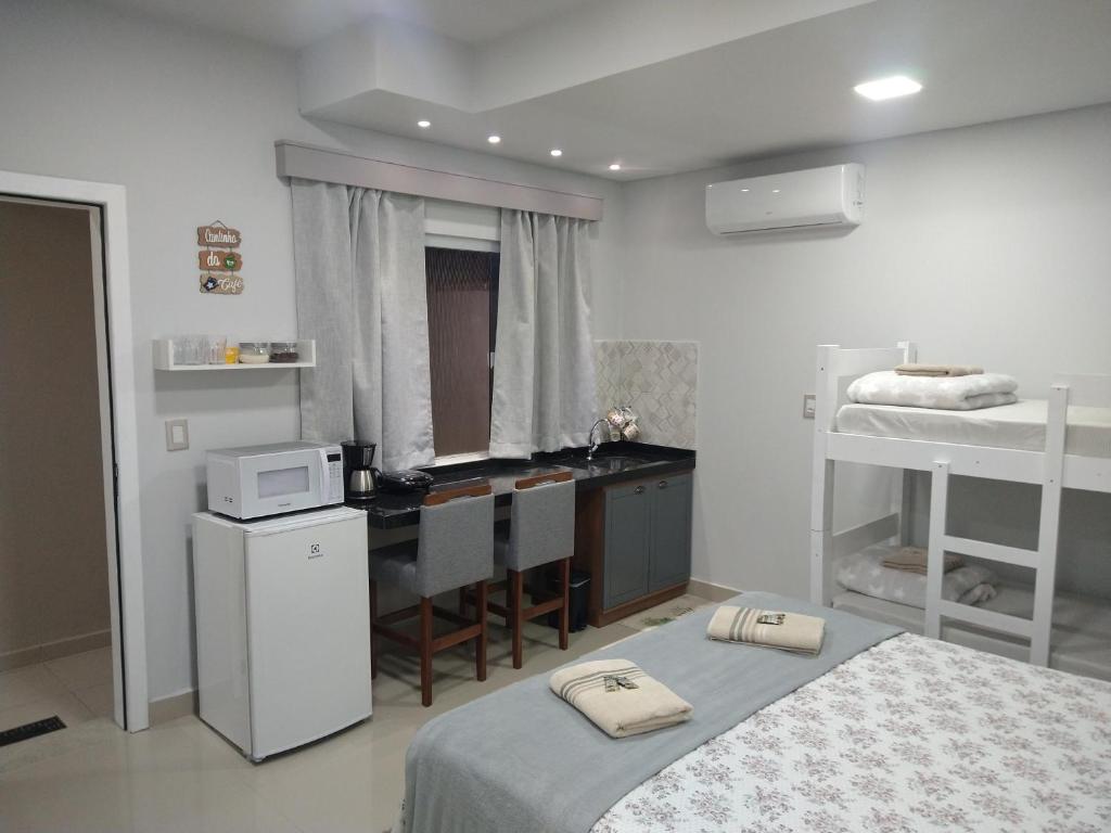 佩尼亚Cantinho da Vila Hospedagem的客房设有两张床、一间厨房和一张书桌