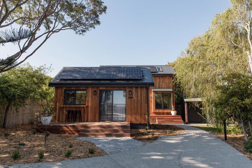 比舍诺Bicheno Garden Cottages的车道上带太阳能屋顶的木屋