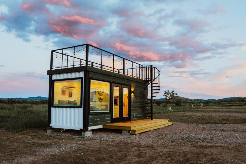 阿尔派恩New Starry Night Shipping Container Home的坐在田野顶上的一个小房子