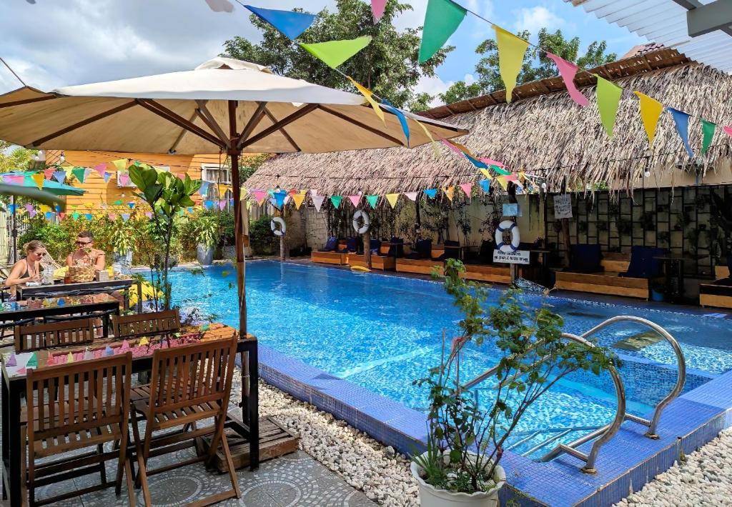 贡布Yellow Star Hostel的一个带桌子和遮阳伞的游泳池