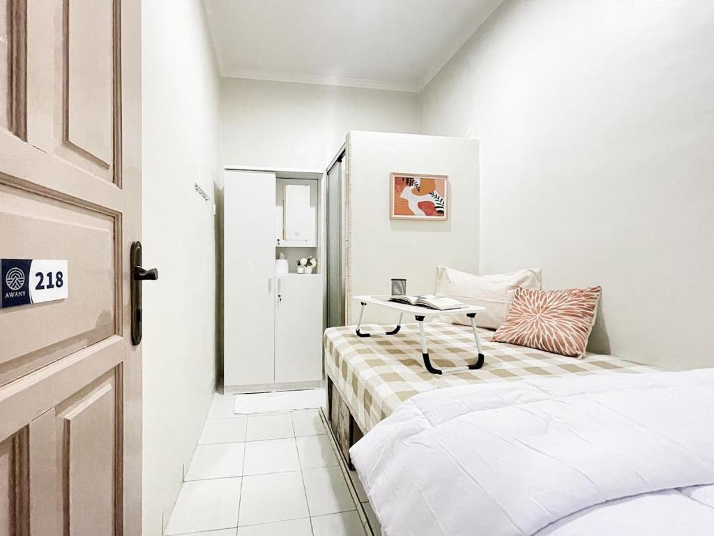 雅加达Kos Awany CoLiving的一间白色卧室,配有两张床和一扇门