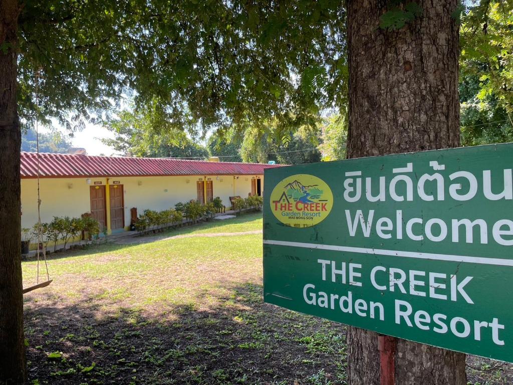 湄宏颂The Creek Garden Resort Huainamrin ห้วยนำ้ริน的树旁的小溪花园度假区的标志