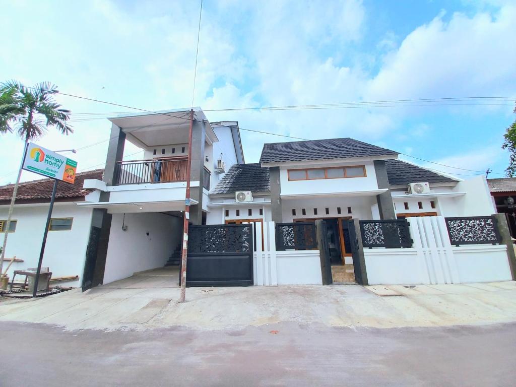 斯勒曼Homestay Jogja Prambanan By Simply Homy的白色的房子,设有门廊和阳台