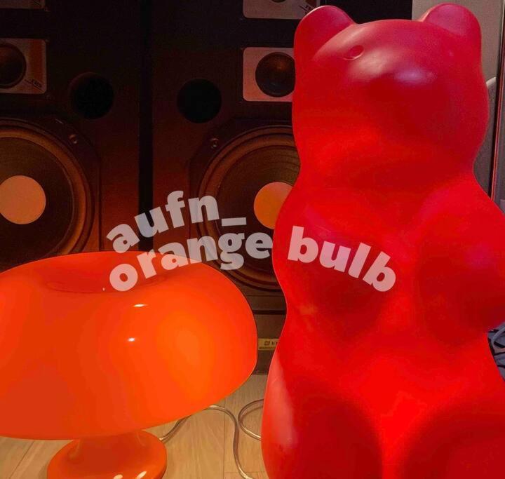 首尔Aufn Orange Bulb的一只红色泰迪熊坐在气球旁边