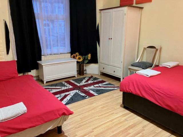伦敦Comfy rooms. Shared East London Homestay.的一间卧室设有两张床、一把椅子和一个窗户。
